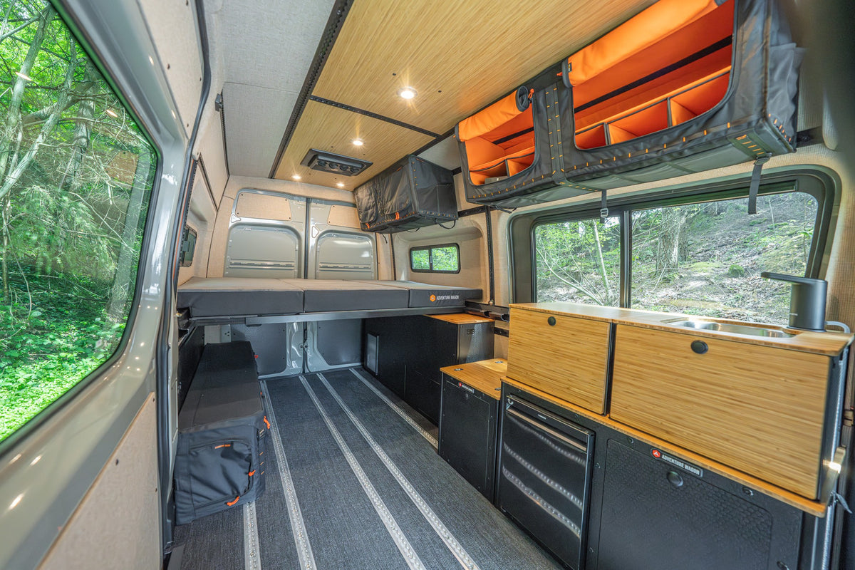 Finished camper van with cabinetry, bed platform, and open Smartfloor rails