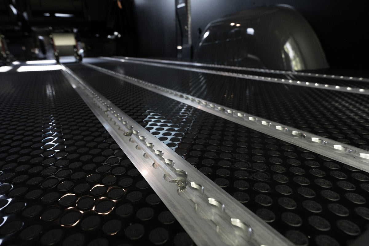 Close-up of aluminum Smartfloor rails installed in a textured black floor